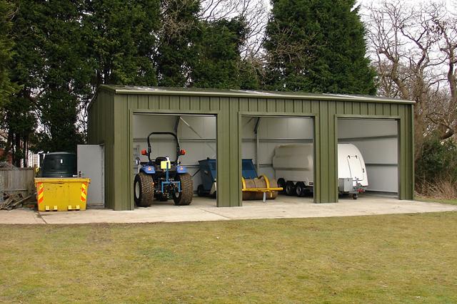 Farm machinery stored inside three open bays of a builing